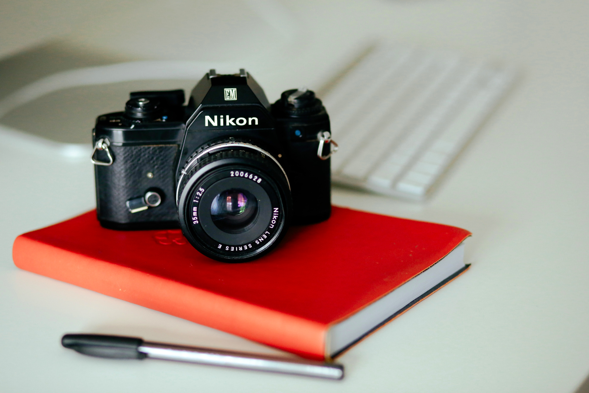 Camera on red notebook with pen and computer - picture day